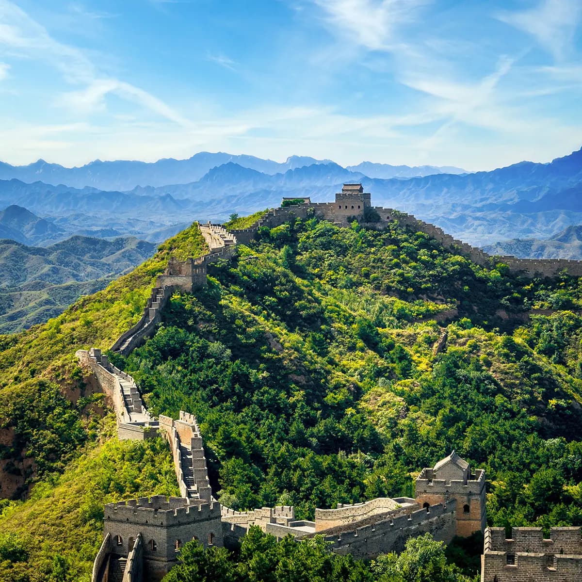 Ein Abschnitt der Großen Mauer mit Wachtürmen über bewaldeten Bergrücken nördlich von Peking