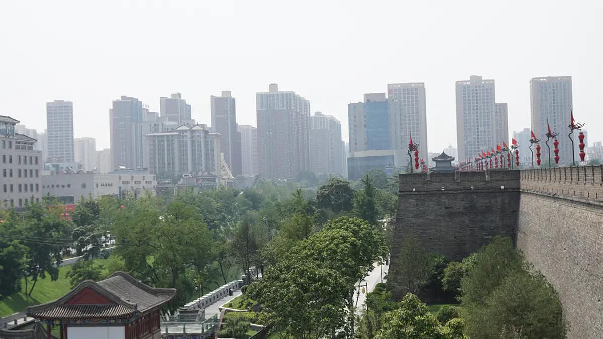 Die Ming-Stadtmauer von Xi'an mit roten Fahnen, davor der Parkgürtel, dahinter die moderne Stadt