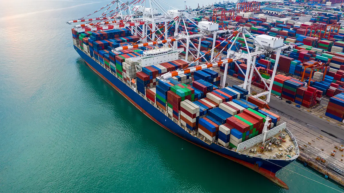Containerschiff im Terminal – Containerstapel im Hintergrund